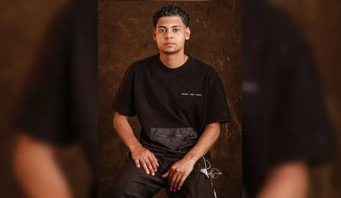 Jovem que desapareceu em Ponta Grossa sentado, com fundo marrom