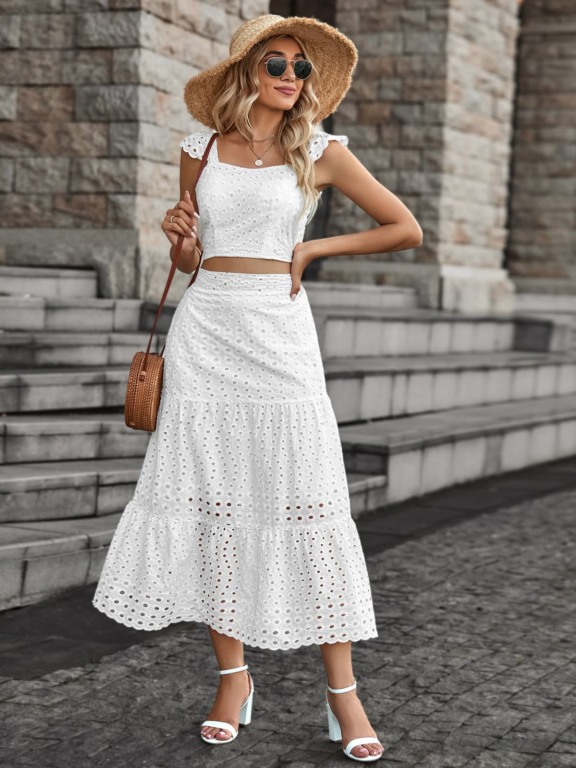 Mulher branca e loira utilizando um cropped branco com uma saia midi branca.
