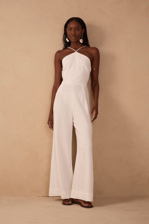 Mulher negra utilizando um macacão branco como look para o réveillon 2025.