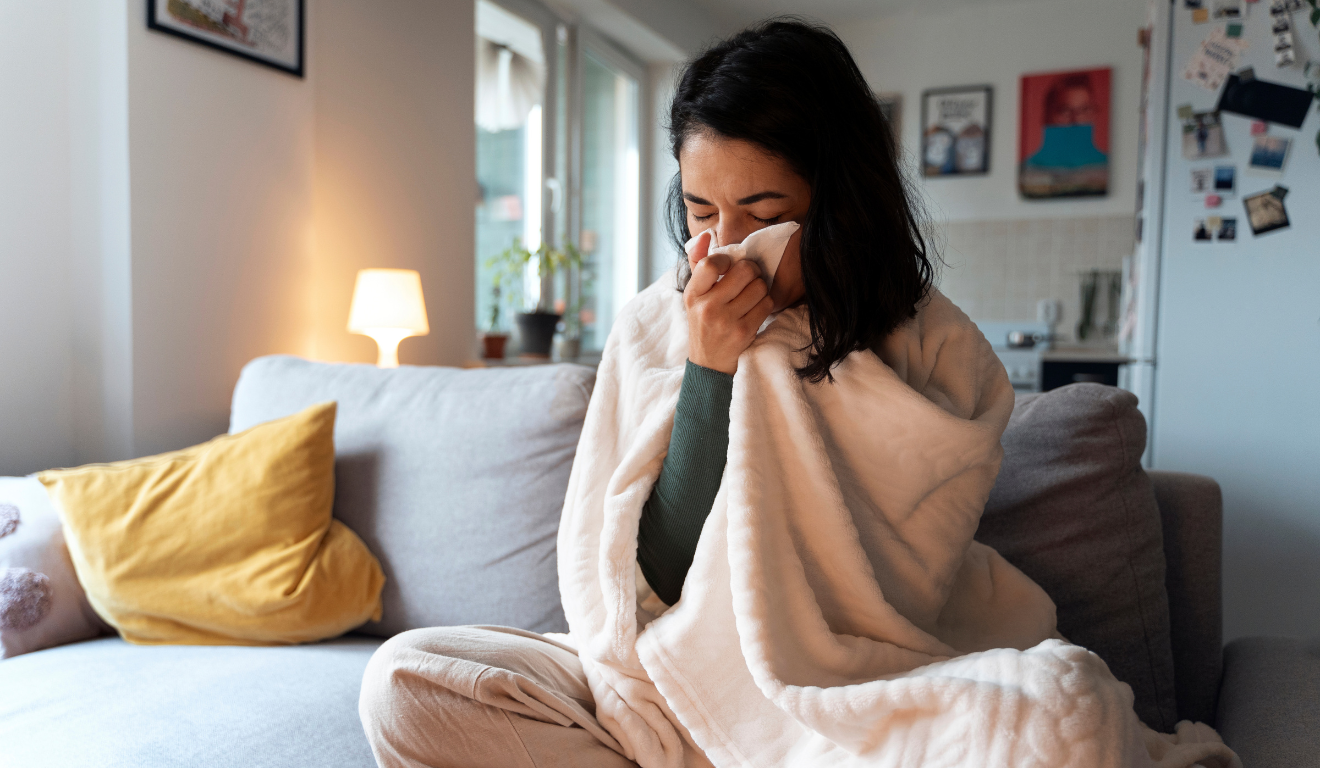 Imagem ilustrativa de mulher branca de cabelo preto com um lenço sobre a boca, indicando que está doente; os sintomas da Gripe K são os mesmos de uma gripe sazonal.