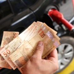 Imagem de frentista com dinheiro, ao lado de carro e bomba de combust&iacute;veis; imagem alusiva a alta no pre&ccedil;o desses produtos