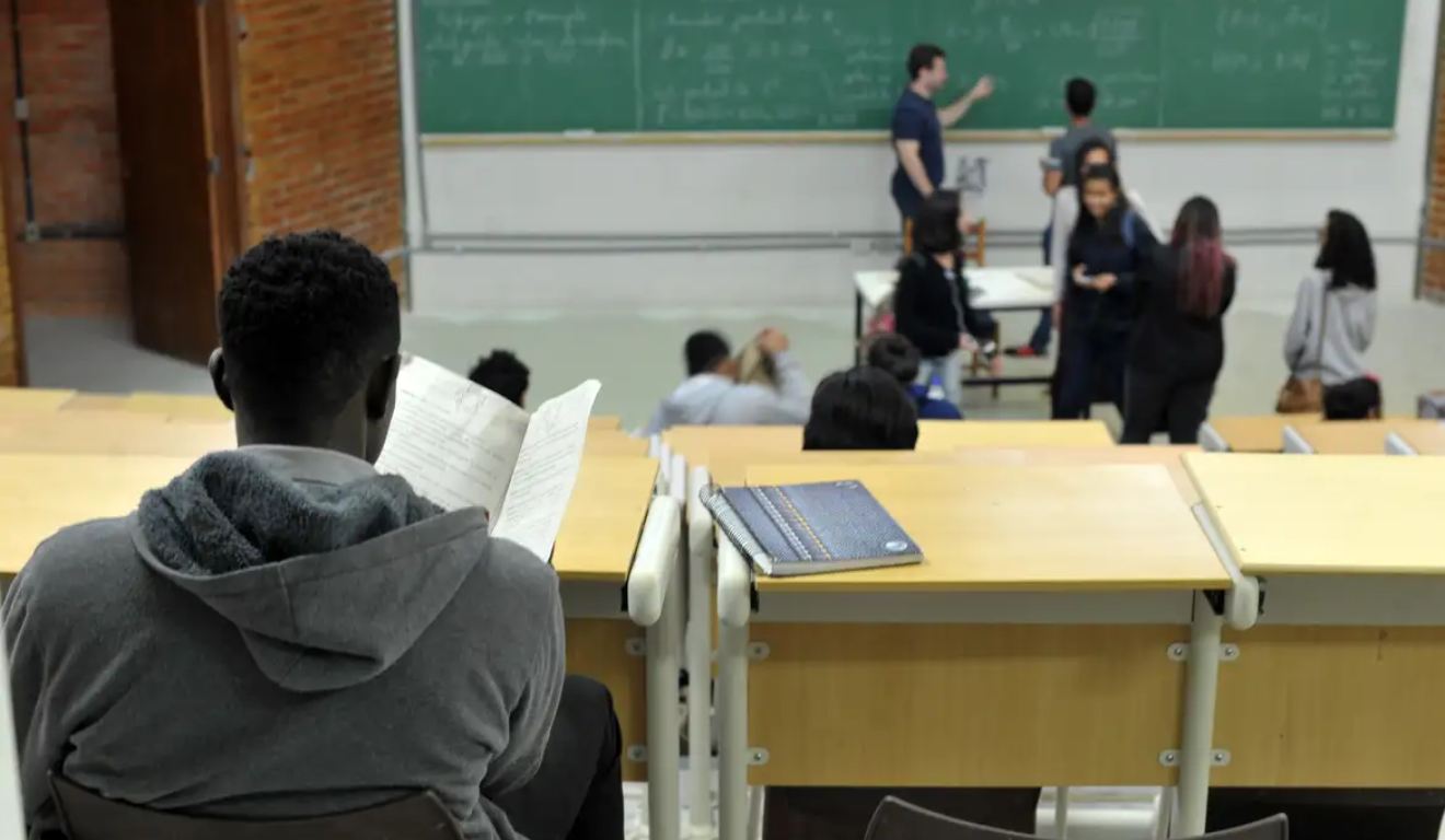 Estudante negro admitido por meio de cotas raciais assiste aula em universidade pública.