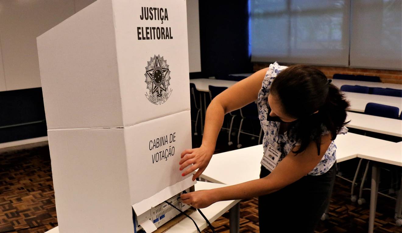 Funcionária da Justiça Eleitoral inspeciona a urna eletrônica antes do início da votação nas eleições de 2022, em Curitiba