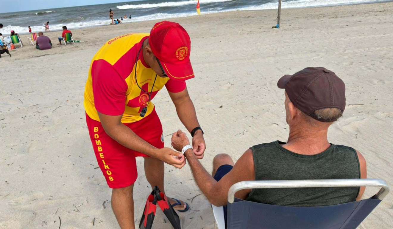 Idoso colocando pulseirinha de identificação no litoral do Paraná