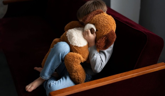 criança abusada escondida atrás de urso de pelúcia