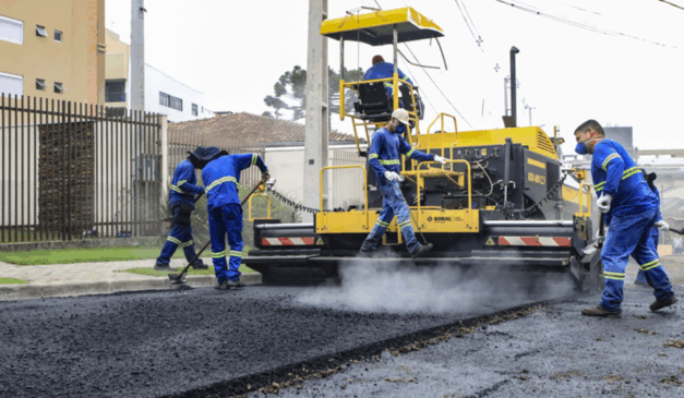 Máquina e trabalhadores pavimentando o asfalto de uma rua, em Curitiba. 25 vias serão requalificadas nos bairros Capão Raso e Novo Mundo. As obras fazem parte do projeto Novo Inter 2.