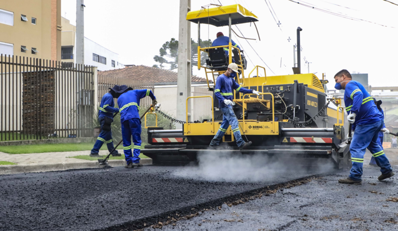Máquina e trabalhadores pavimentando o asfalto de uma rua, em Curitiba. 25 vias serão requalificadas nos bairros Capão Raso e Novo Mundo. As obras fazem parte do projeto Novo Inter 2.